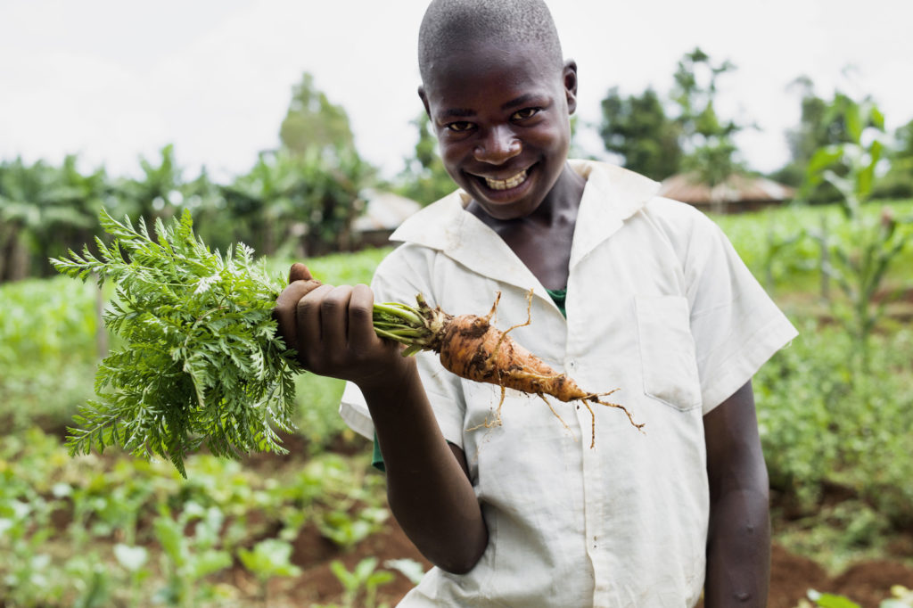 Kenyan boy in garden holding carrot